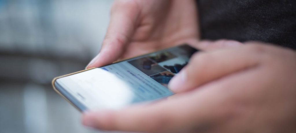 Close-up of hands using a smartphone with a touchscreen, emphasizing mobile technology.